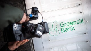 Eine Kamera filmt das Schild der Greensill-Bank.