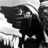 Filmszene: Bruno Ganz sitzt auf der Schulter einer übergroßen Engels-Statue 