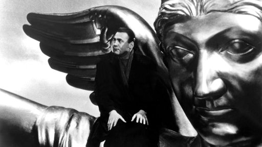 Filmszene: Bruno Ganz sitzt auf der Schulter einer übergroßen Engels-Statue 
