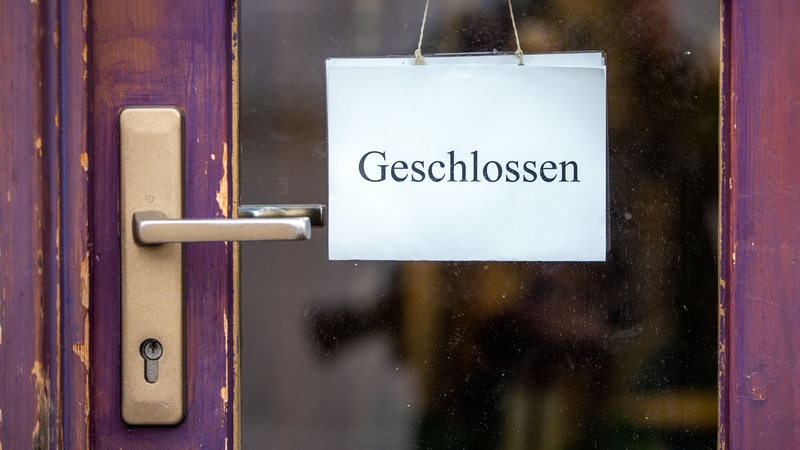 Ein Schild mit der Aufschrift "Geschlossen" hängt an der Tür eines Ladengeschäfts