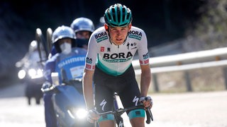 Lennard Kämna fährt Rad bei der Katalonien-Rundfahrt. Hinter ihm fahren zwei Guards.