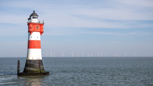 Ein rot-weiß-gestreifter Leuchtturm steht im Meer.