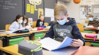 Schulkinder mit Mund-Nase-Bedeckung in einer Grundschule.