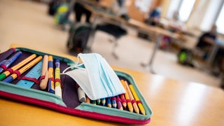 Der Ersatz-Mundschutz einer Schülerin liegt während des Unterrichts in einer vierten Klasse einer Grundschule auf dem Federmäppchen der Schülerin.