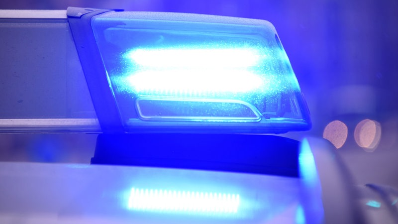 Ein Blaulicht leuchtet auf dem Dach von einem Streifenwagen der Polizei an einer Unfallstelle.
