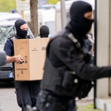 Polizisten verladen bei einer Razzia Kartons in einen Lastwagen. 