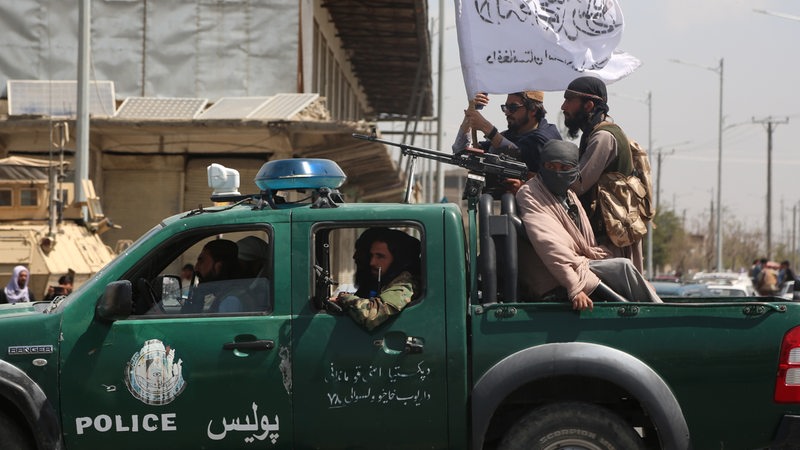 Taliban Kämpfer mit Fahnen auf einem Police Truck in Kabul