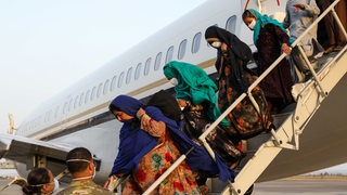 Angehörige von Helfern aus Afghanistan verlassen ein Flugzeug.