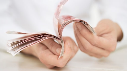Eine Frau hält mehrere 10-Euronoten in der Hand und blättert sie (Symbolbild)