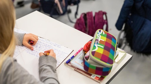 Eine Schülerin einer fünften Klasse sitzt während in ihrem Klassenzimmer und schreibt.