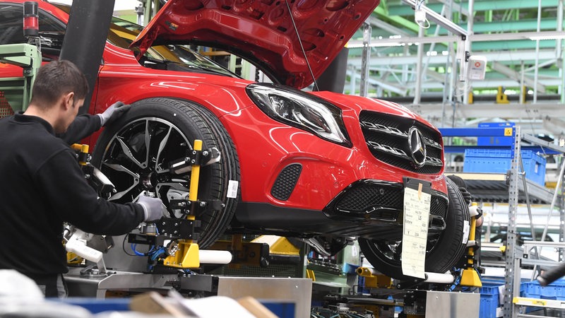 Mercedes-Mitarbeiter montiert Reifen an ein Fahrzeug (Archivbild)