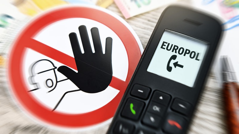 Telefonhörer mit eingehendem Fake-Anruf von Europol und Warnschild, Symbolfoto Telefonbetrug
