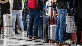 Flugreisende warten mit Gepäck an einem Terminal (Archivbild)