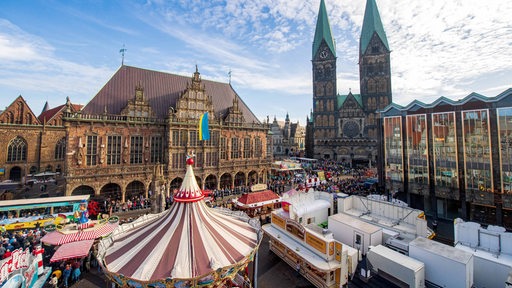 Der Freimarktsumzug zieht durch die Innenstadt, vorbei am Rathaus und Roland auf dem Marktplatz. 