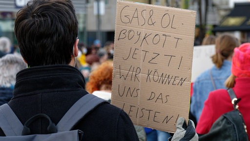 Ein Teilnehmer hält bei einer Demonstration von Fridays for Future gegen den Krieg in der Ukraine ein Schild mit Aufschrift "Gas und Öl Boykott jetzt!"