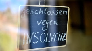 Ein Schild "Geschlossen wegen Insolvenz" hängt an einem Geschäft