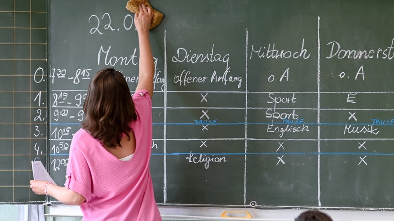 Eine Lehrerin steht an einer Tafel und wischt (Archivbild)