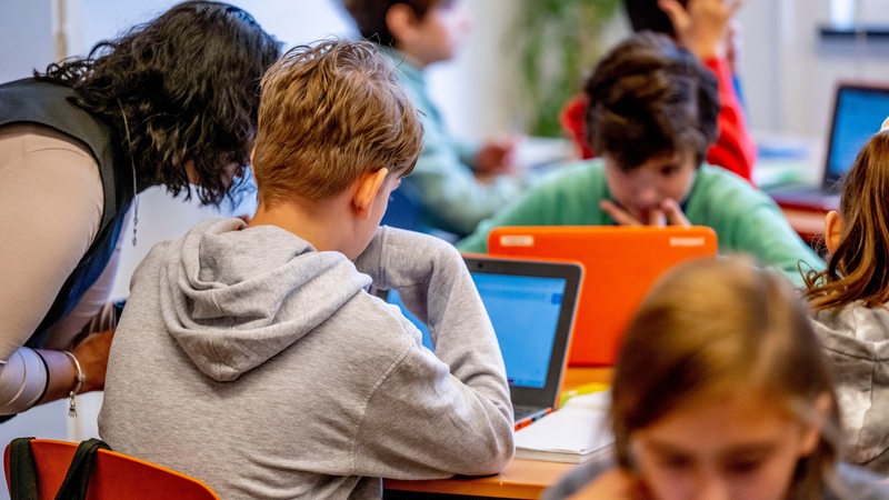 Eine Lehrerin hilft einem Schüler während des Unterrichts (Symbolbild)