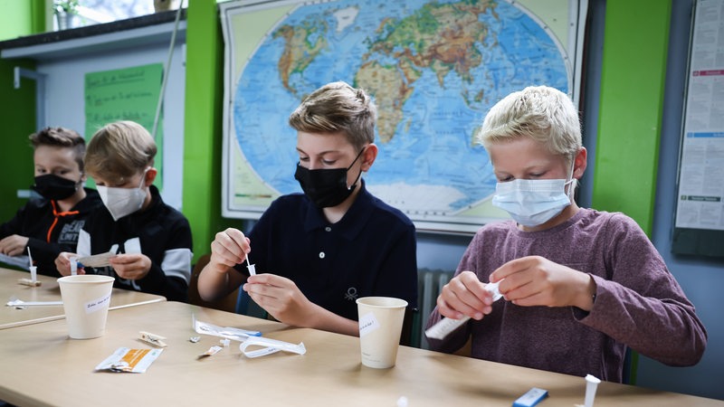 Schüler mit Masken machen einen Corona-Schnelltest