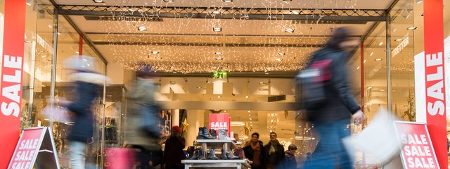 Menschen beim Einkaufen vor einem weihnachtlich beleuchteten Kaufhaus (Symbolbild)