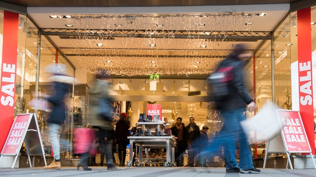 Menschen beim Einkaufen vor einem weihnachtlich beleuchteten Kaufhaus (Symbolbild)
