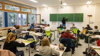 Schülerinnen und Schüler einer fünften Klasse sitzen in ihrem Klassenzimmer (Archivbild)