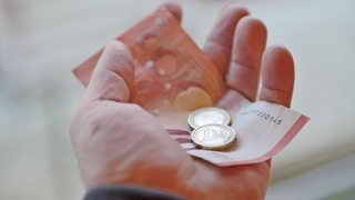 Eine Hand hält 12 Euro in der Hand.
