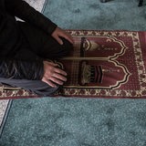 Teilaufnahme eines betenden Mannes auf Knien in einer Moschee