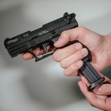 Hände laden eine Schreckschuss-Pistole "Walther P22" mit einem Magazin.
