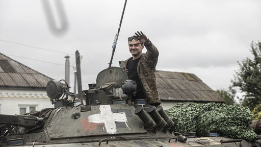 Ukrainischer Soldat grüßt in Charkiw von einem Panzer