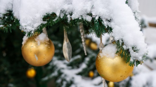 Schneebedeckter Weihnachtsbaum mit goldenen Kugeln (Symbolbild)