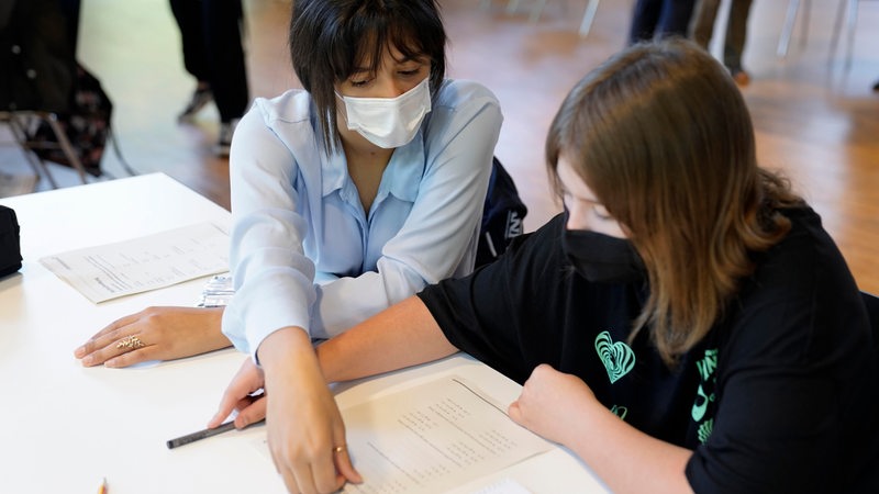 Eine Frau hilft einer Schülerin in der Schule beim Lernen
