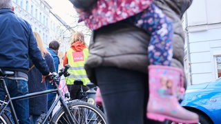 Ein Kind sitzt auf dem Arm einer Erzieherin, die zusammen mit Kolleginnen streikt.