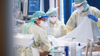 Krankenschwestern und Ärzt*innen versorgen auf der Intensivstation für Covid 19 einen Patienten