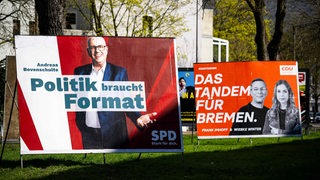 Wahlplakate der SPD und der CDU stehen am Straßenrand.