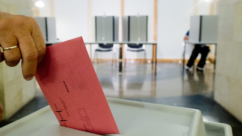 Ein Mann wirft in einem Wahlraum seinen Stimmzettel in eine Wahlurne (Archivbild)