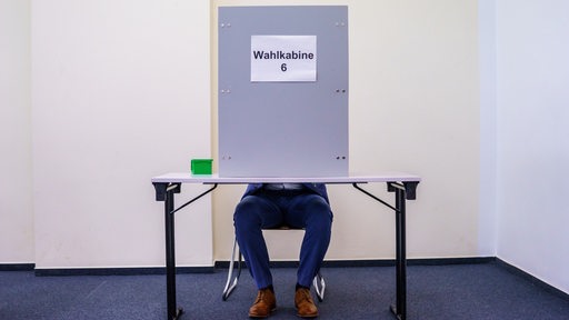 Ein Mann sitzt in der Wahlkabine
