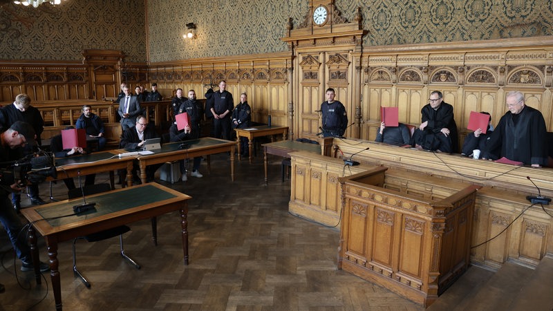 Vier Angeklagte warten in einem Saal des Landgerichtes in Bremen mit ihren Verteidigern auf ihren Prozessbeginn. 