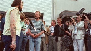 Der Entführer Hans-Jürgen Rösner steht mit einer Pistole in der Hand vor Journalisten.