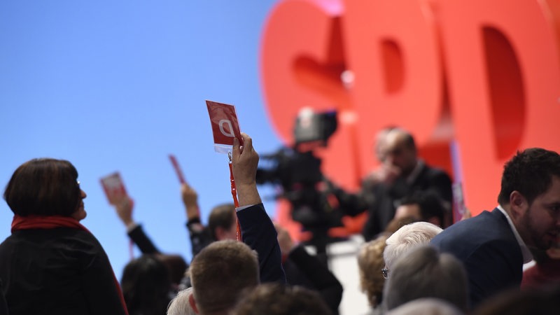 Hände mit Stimmkarten vor SPD-Logo