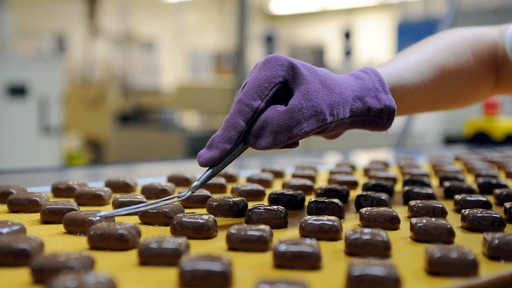 Manuell wird bei Hachez Chocolade in Bremen ein Muster auf Pralinen aufgebracht.