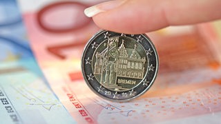 Ein 2-Euro-Stück mit Bremer Motiven auf mehreren Euro-Banknoten.