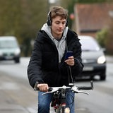 Ein Radfahrer mit Kopfhörern auf den Ohren und einem Handy in der Hand.