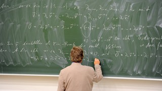 Ein Professor schreibt an eine Tafel (Symbolbild)