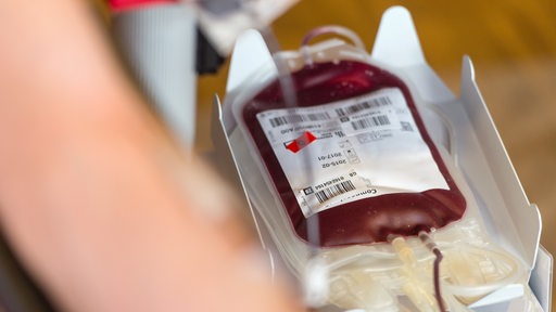 Ein Beutel mit Spenderblut liegt neben einem Blutspender.