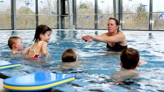 Eine Schwimmlehrerin mit ihren Schülern im Wasser.