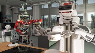 Einer der Roboter des Forschungsinstituts "Artificial Intelligence (AI)" an der Universität in Bremen nimmt am 08.03.2017 einen Kochtopf mit zubereitetem Popcorn vom Herd. 