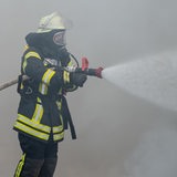 Zwei Feuerwehrleute mit Atemschutz löschen einen Brand. (Symbolbild)
