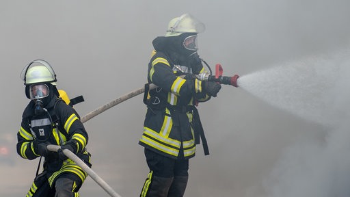 Zwei Feuerwehrleute mit Atemschutz löschen einen Brand. (Symbolbild)