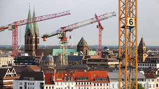 Blick auf die Dächer der Bremer Innenstadt, darüber jede Menge Baukräne (Bildmontage).